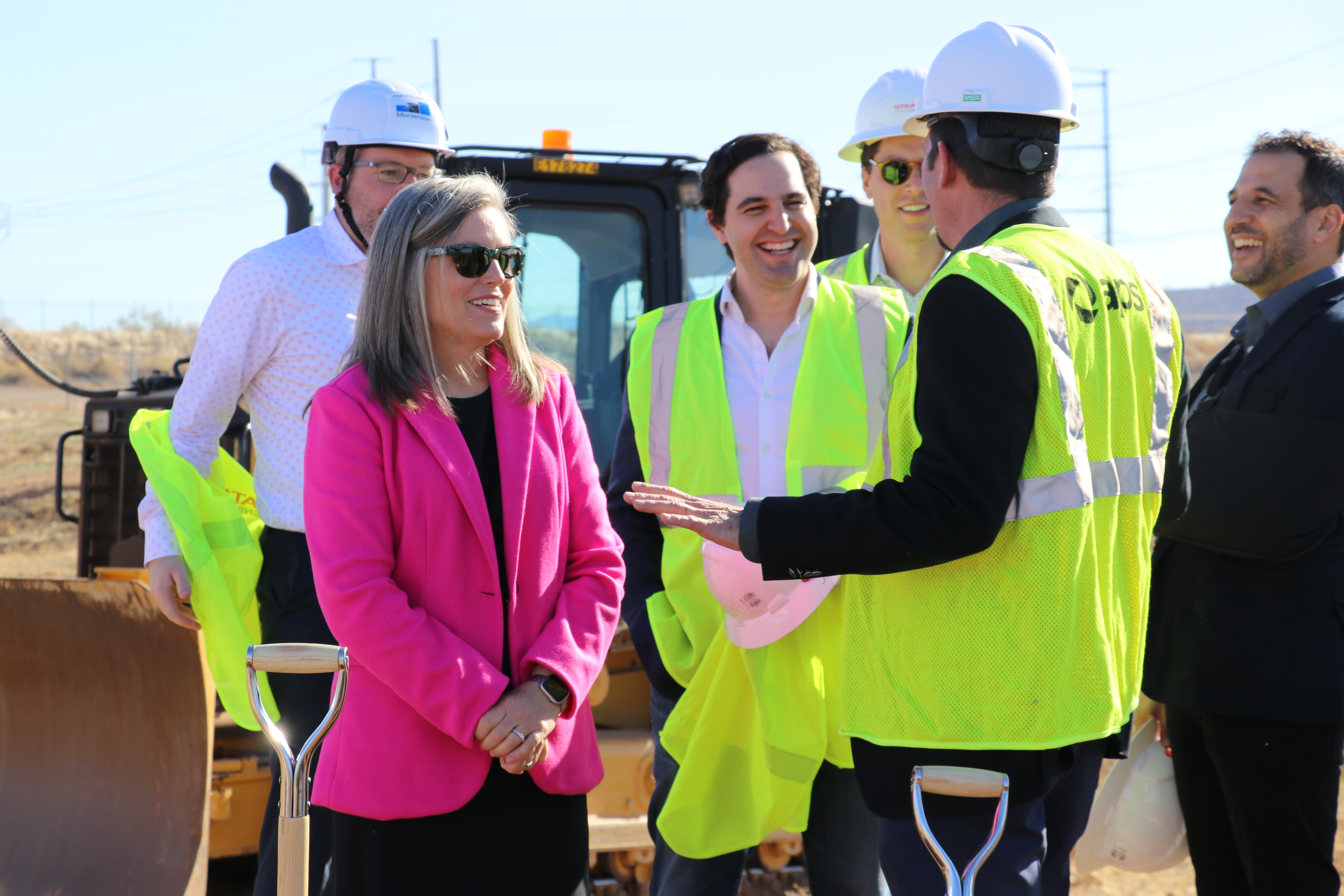 Governor Katie Hobbs talking with executives in construction gear on a construction site.