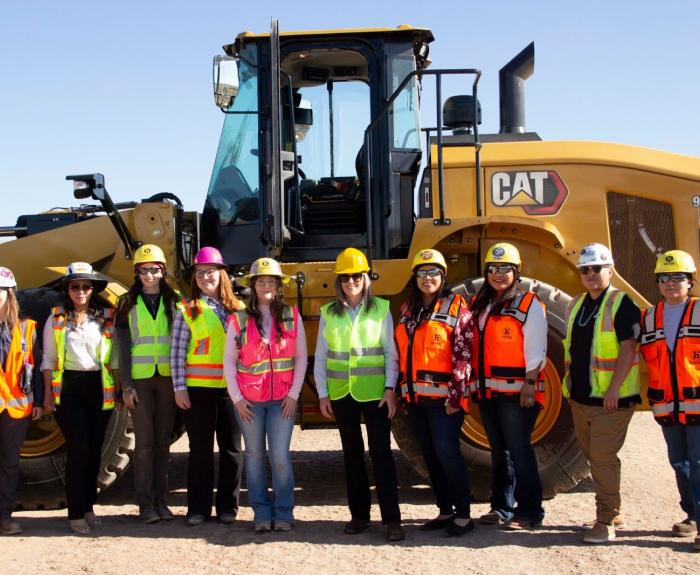 Governor Hobbs and others wearing P.P.E. in front of a large bulldozer.