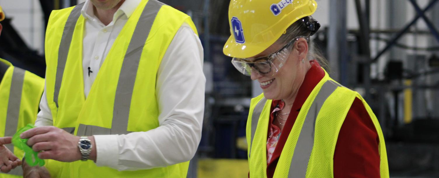 Governor Hobbs putting on green rubber gloves in full personal protection equipment.